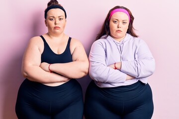 Obraz premium Young plus size twins wearing sportswear skeptic and nervous, disapproving expression on face with crossed arms. negative person.