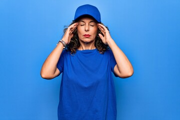 Middle age beautiful delivery woman wearing blue uniform and cap over isolated background with hand on head, headache because stress. Suffering migraine.
