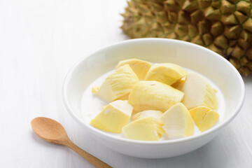 Thai dessert, sliced durian fruit with coconut milk in a bowl on white table background