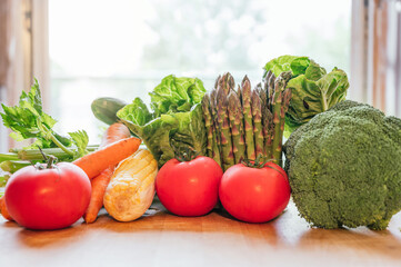 Fresh vegetables on a wooden table, vegetables such as tomatoes, asparagus, broccoli, carrots, corn and lettuce.