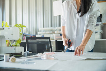 Young female fashion designer working on her designs in the studio. Fashion designer drawing sketches for new collection. Beautiful fashion woman designer drawing in studio .