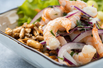 Close up shot of a shrimp ceviche served in a rustic bowl, isolated over a textured rustic gray wooden background.