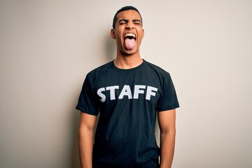 Young handsome african american worker man wearing staff uniform over white background sticking tongue out happy with funny expression. Emotion concept.