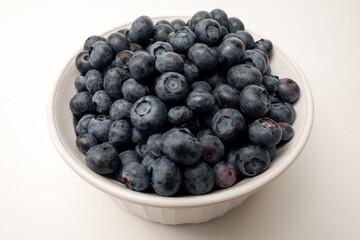 A bowl full of fresh blueberries shot from a high angle on a white background