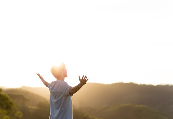 Happy young man with arms raised and sunset in the background