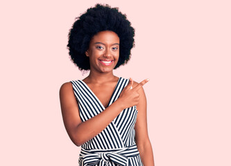 Young african american woman wearing casual clothes cheerful with a smile of face pointing with hand and finger up to the side with happy and natural expression on face