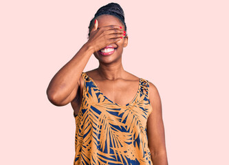 Young african american woman wearing casual clothes smiling and laughing with hand on face covering eyes for surprise. blind concept.