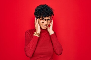 Young beautiful african american afro woman wearing turtleneck sweater and glasses covering ears with fingers with annoyed expression for the noise of loud music. Deaf concept.