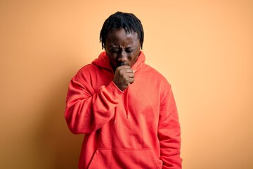 Young african american sporty man wearing sweatshirt with hoodie over yellow background feeling unwell and coughing as symptom for cold or bronchitis. Health care concept.