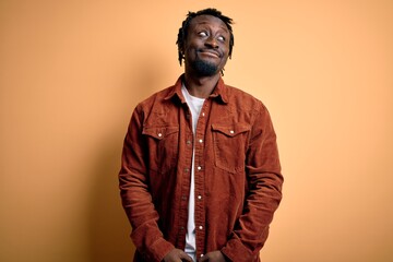 Fototapeta premium Young handsome african american man wearing casual jacket standing over yellow background smiling looking to the side and staring away thinking.