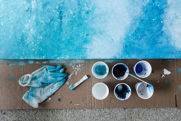 arts and craft hobbies concept, blue and white acrylic painting with colors in plastic cups and...