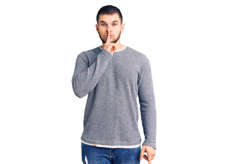 Young handsome man wearing casual sweater asking to be quiet with finger on lips. silence and secret concept.