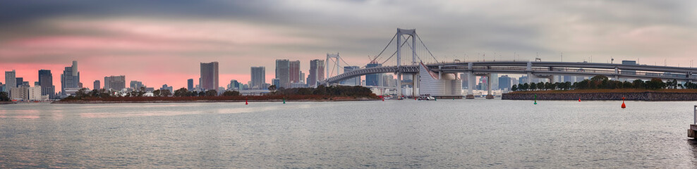 Obraz premium Tokyo Scenic Destinations. Famous Rainbow Bridge in Odaiba Island in Tokyo with Line of Skyscrapers in Background.