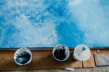 arts and craft hobbies concept, blue and white acrylic painting with colors in plastic cups and...