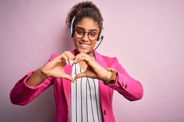 Young african american call center agent girl wearing glasses working using headset smiling in love...