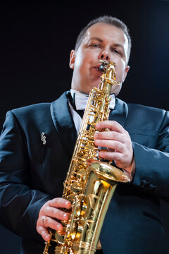 Portrait of Expressive Male Saxophonist Player Against Black