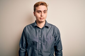 Young handsome redhead man wearing casual shirt standing over isolated white background with serious expression on face. Simple and natural looking at the camera.