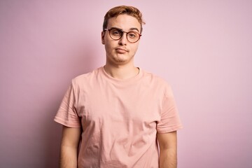 Young handsome redhead man wearing casual t-shirt standing over isolated pink background looking...