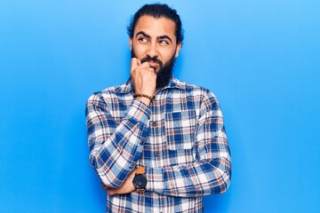 Young arab man wearing casual clothes serious face thinking about question with hand on chin, thoughtful about confusing idea