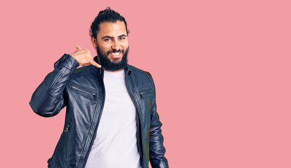 Young arab man wearing casual leather jacket smiling doing phone gesture with hand and fingers like talking on the telephone. communicating concepts.