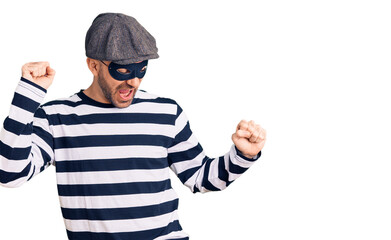 Young handsome man wearing burglar mask dancing happy and cheerful, smiling moving casual and confident listening to music