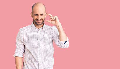 Young handsome man wearing elegant shirt smiling and confident gesturing with hand doing small size sign with fingers looking and the camera. measure concept.