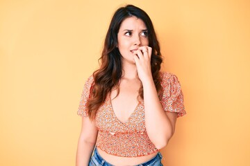 Young beautiful brunette woman wearing casual summer clothes looking stressed and nervous with hands on mouth biting nails. anxiety problem.