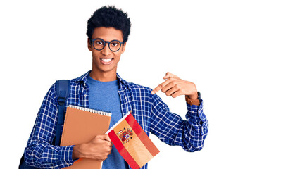 Young african american man wearing student backpack holding spanish flag smiling happy pointing with hand and finger