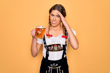 Beautiful blonde german woman with blue eyes wearing octoberfest dress drinking jar of beer stressed with hand on head, shocked with shame and surprise face, angry and frustrated. Fear and upset.