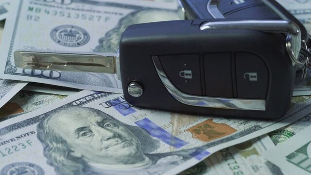 Close-up of car keys on stack of hundred dollar bills rotating. Buying car concepts.