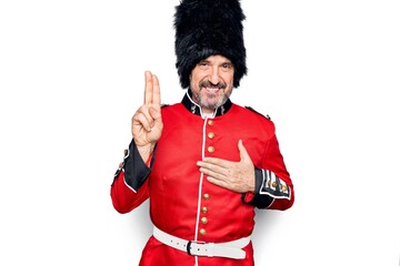 Middle age handsome wales guard man wearing traditional uniform over white background smiling...