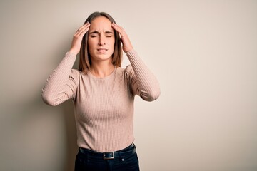 Young beautiful woman wearing casual sweater standing over isolated white background with hand on head for pain in head because stress. Suffering migraine.