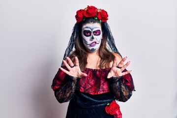 Young woman wearing day of the dead costume over white disgusted expression, displeased and fearful doing disgust face because aversion reaction.