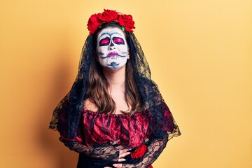 Young woman wearing day of the dead costume over yellow with hand on stomach because nausea, painful disease feeling unwell. ache concept.