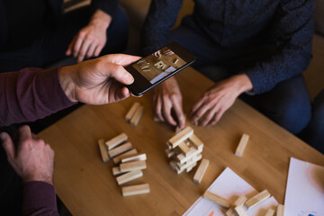 A man takes photos of them playing jenga.