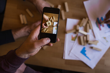 A man takes photos of them playing jenga.