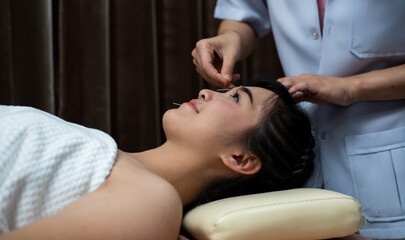 woman lying on a table in an alternative medicine spa having an acupuncture and reiki treatment...
