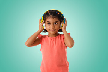 Music,childhood and technology concept.Child with headphones on green background