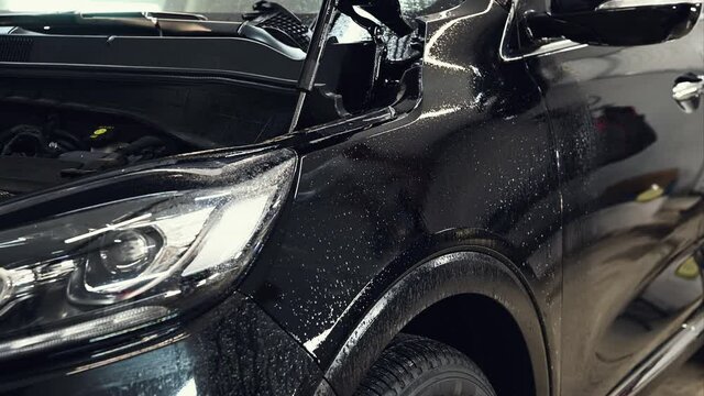 Two man install paint protection film on modern SUV. PPF is polyurethane film applied to car surface to protect the paint from stone chips, bug splatter, and abrasion.