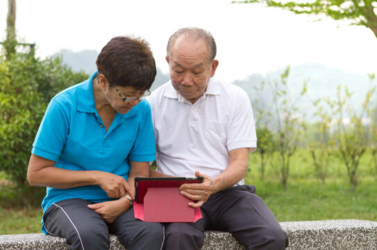 Elderly Chinese Couple Looking At The Mobile Tablet