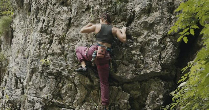 Female paralympic climber woman athlete with missing fingers on left hand rock climb search to hold grip attach carabiner rope ascend outdoors lifestyle sport in nature