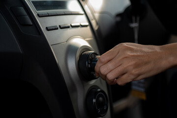 Young Woman Turning on car air conditioning system,