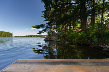 Perspective of a wooden dock on a calm lake in Muskoka, Ontario Canada.