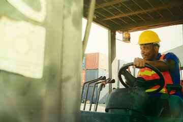African-American male workers wear safety clothing in a warehouse carrying cargo containers ,...