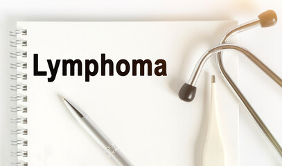 On the table are a stethoscope, a thermometer, a pen and a notebook with the inscription -Lymphoma