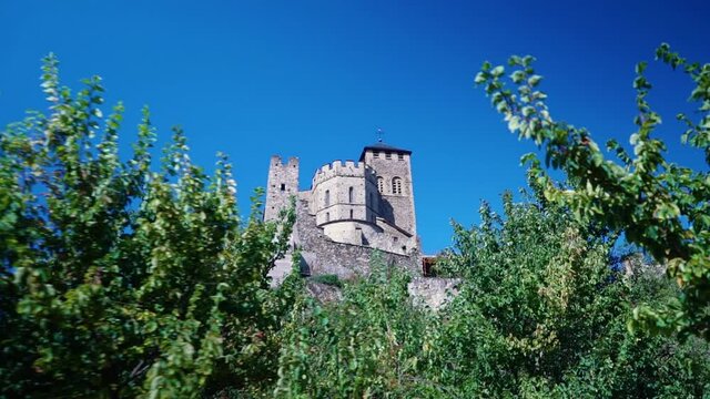 Truck shot of European medieval castle tower through green bushes in summer