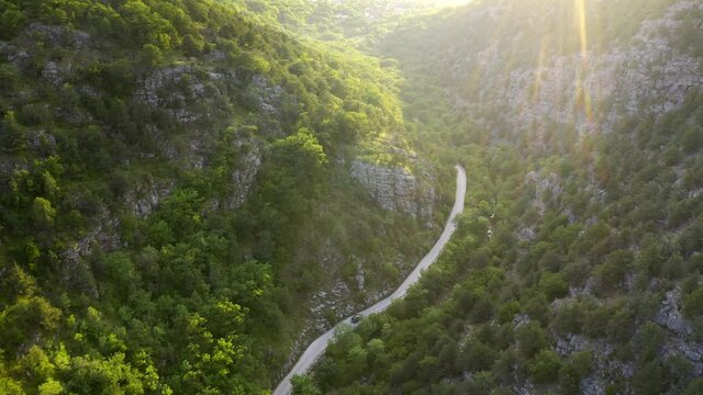 Car mooving on road into mountain canyon at sunset. 