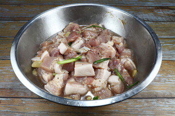 Chopped Marinated belly pork (streaky pork) with cutting ginger and spring onion in the aluminium bowl. Preparation food in Thai kitchen.