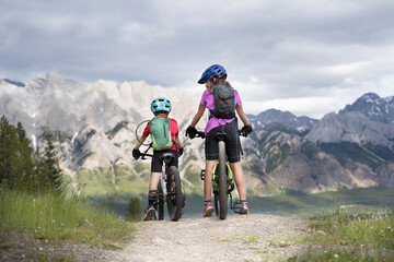 A big sister and her little brother on a family mountain bike ride in Kananaskis Alberta Canada. - Powered by Adobe