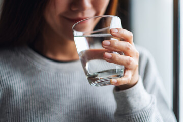 Closeup image of a beautiful young asian woman holding a glass of water to drink